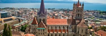 Vue aérienne Cathédrale de Lausanne, toits rouges, lac, montagnes.