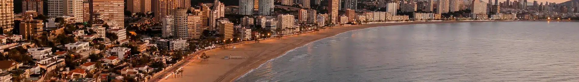 **Alicante Elche au coucher du soleil, la mer au premier plan.**